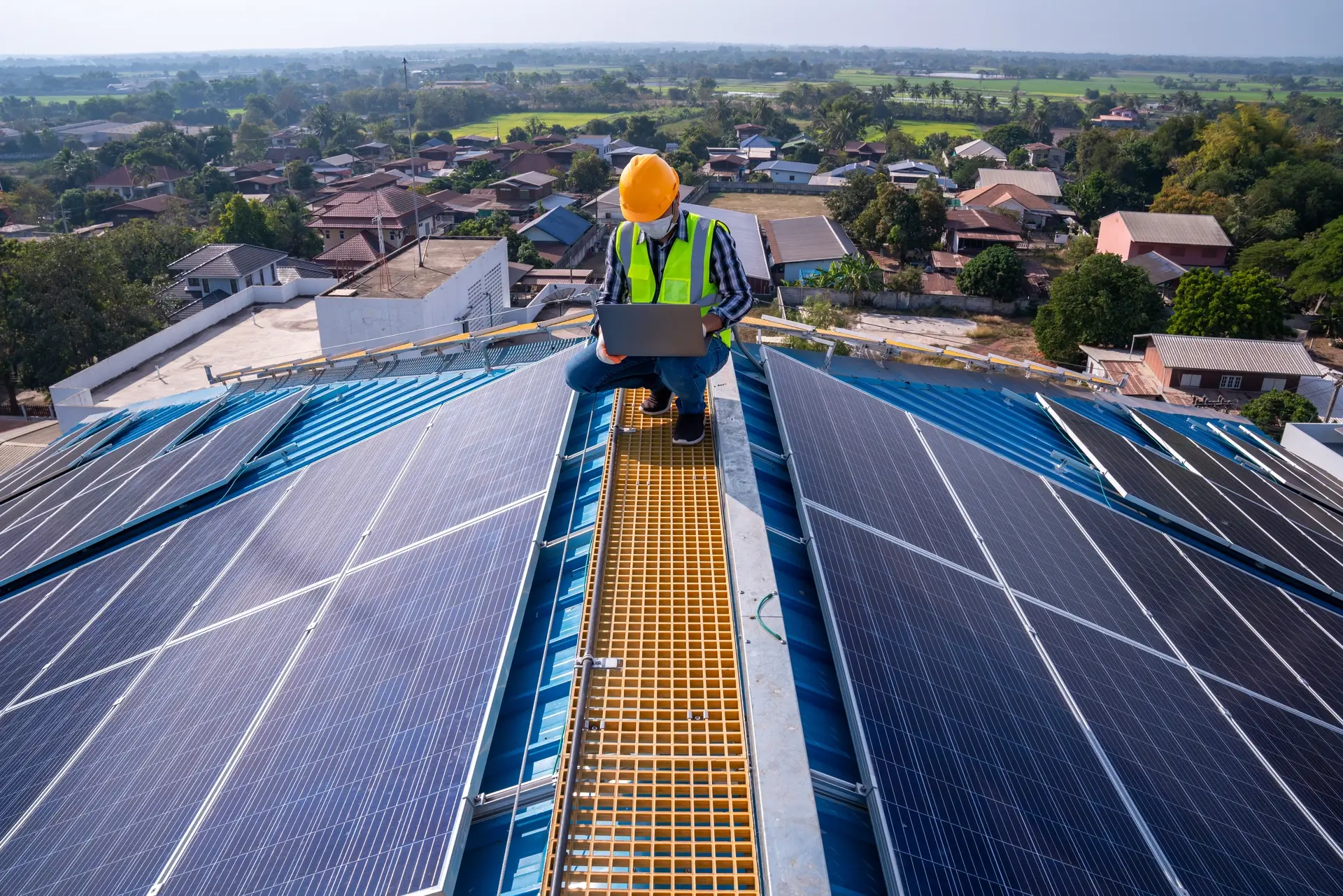 A technician working in a laptop and providing solar energy system in a rooftop